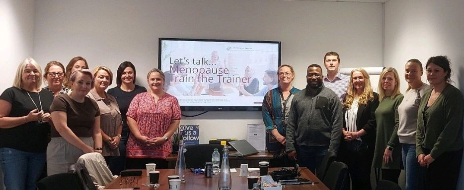 Group of people standing together in a conference room with a presentation screen behind them.