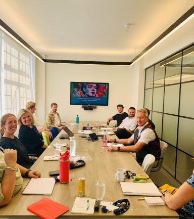 A group of people seated at a long table in a modern conference room.
