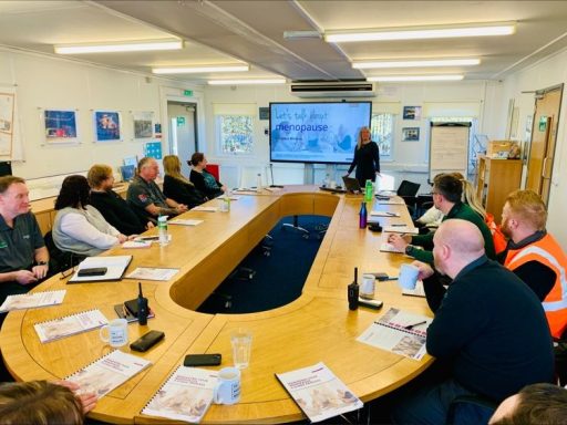 A meeting in a conference room with participants around a large oval table.
