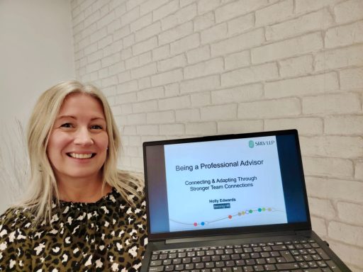 A smiling woman holds a laptop displaying a presentation titled "Becoming a Professional Advisor."