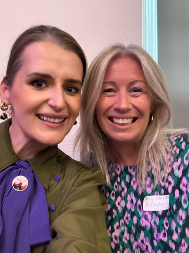 Two women smiling for a selfie, both wearing colourful outfits.