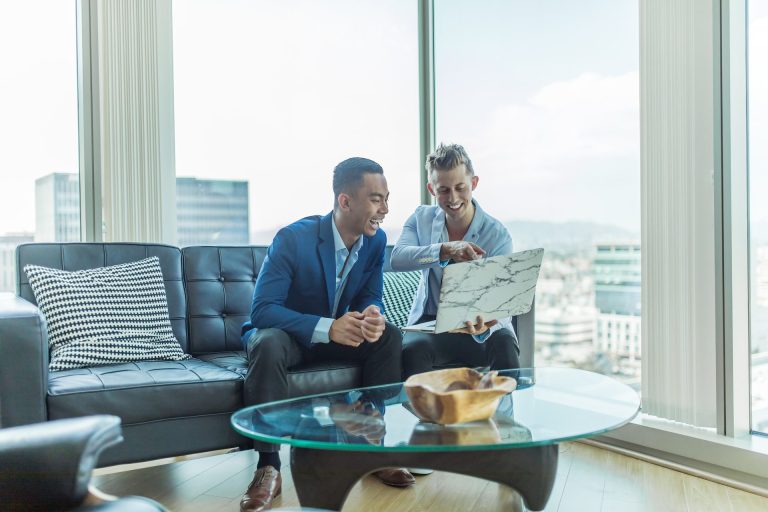 Two professionals discussing plans while seated in a modern office with city views.